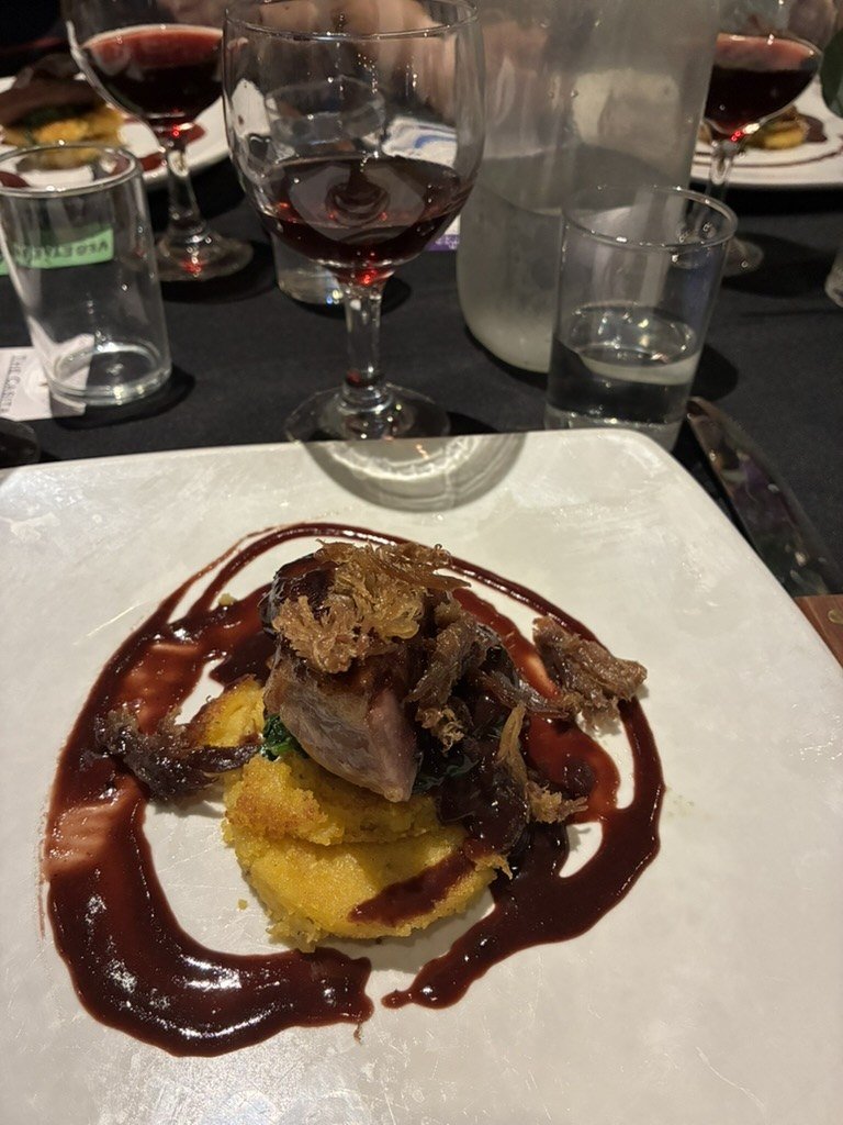 A braised course over polenta with red wine sauce, served alongside a glass of Soaring Wines red